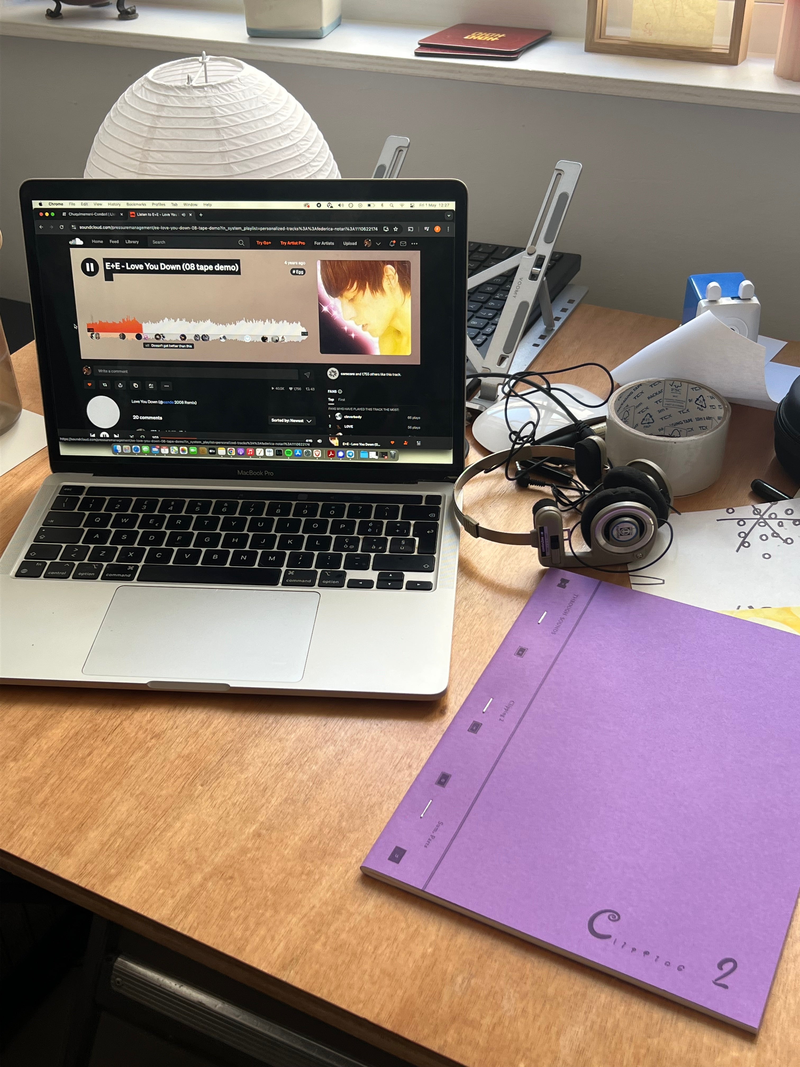 A laptop, headphones, and a purple notebook on a wooden desk.