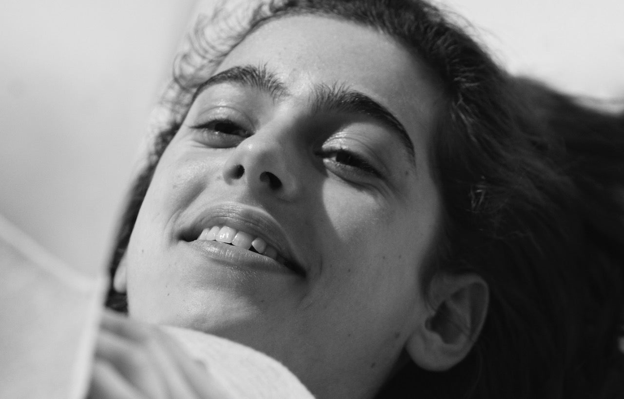 Black and white close-up portrait of a smiling person looking upwards.