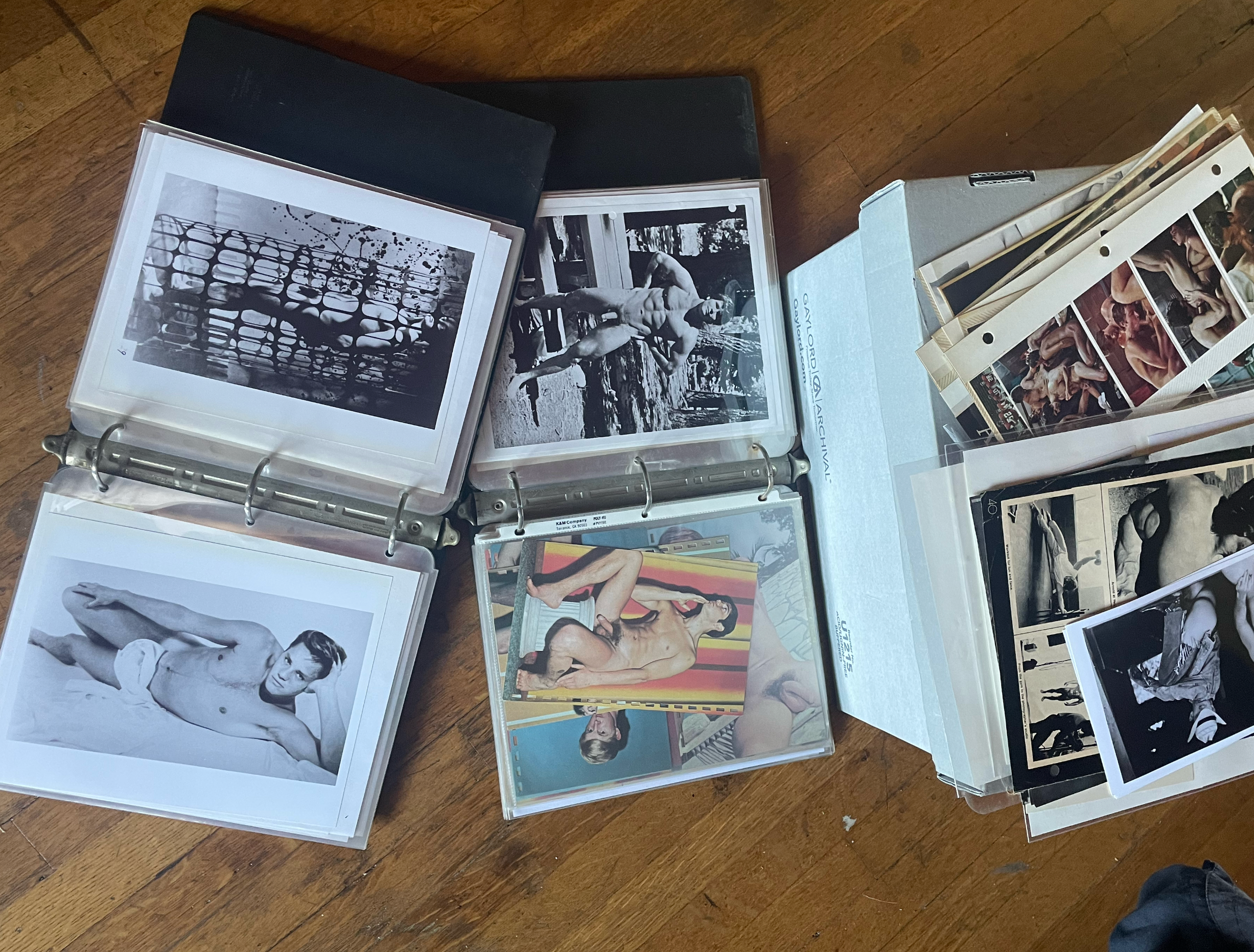 Open binders and folders containing vintage black and white and color photographs of men.
