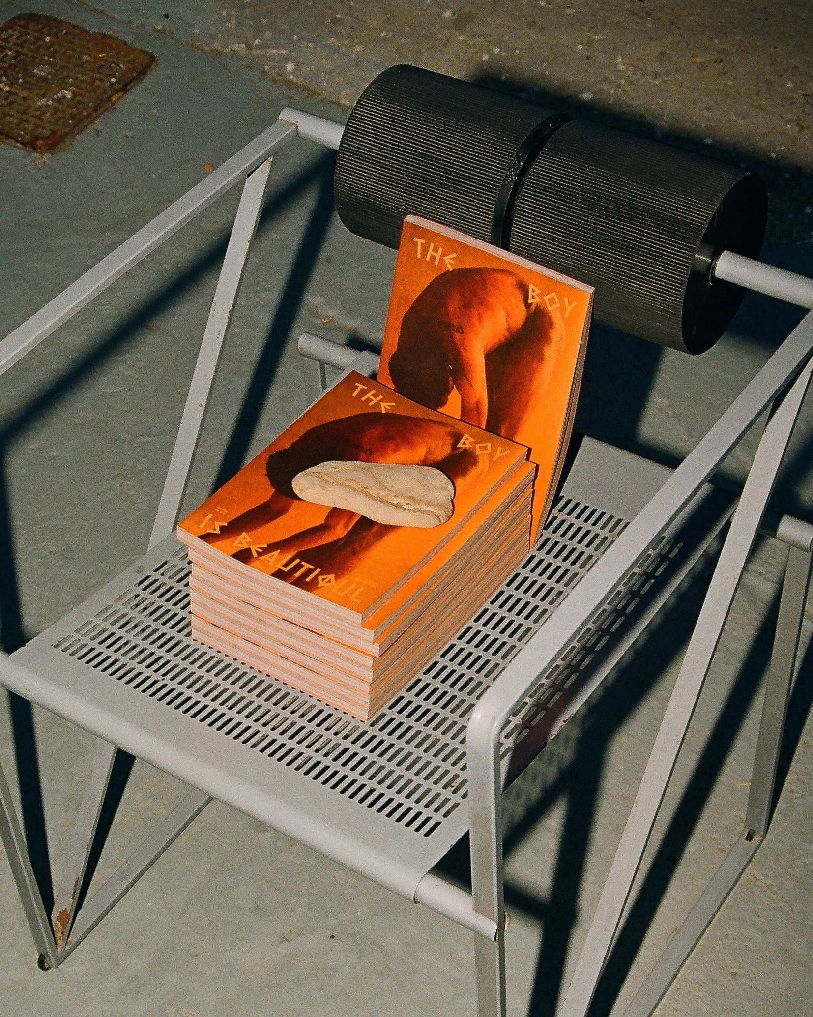 Cover of the book 'THE BOY' resting on a grey metal chair.