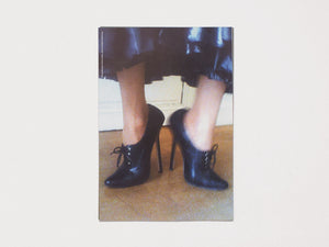 A person wearing black high-heeled shoes, fishnet stockings, and a dark leather skirt.