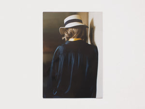 Back view of a person wearing a white hat with a dark band and a dark navy blue shirt.