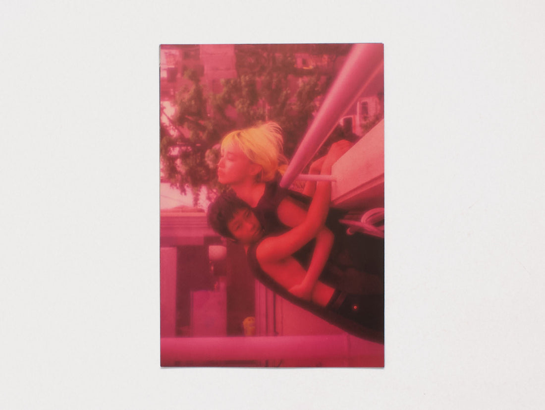 A red-tinted photograph of two people embracing in an outdoor setting.